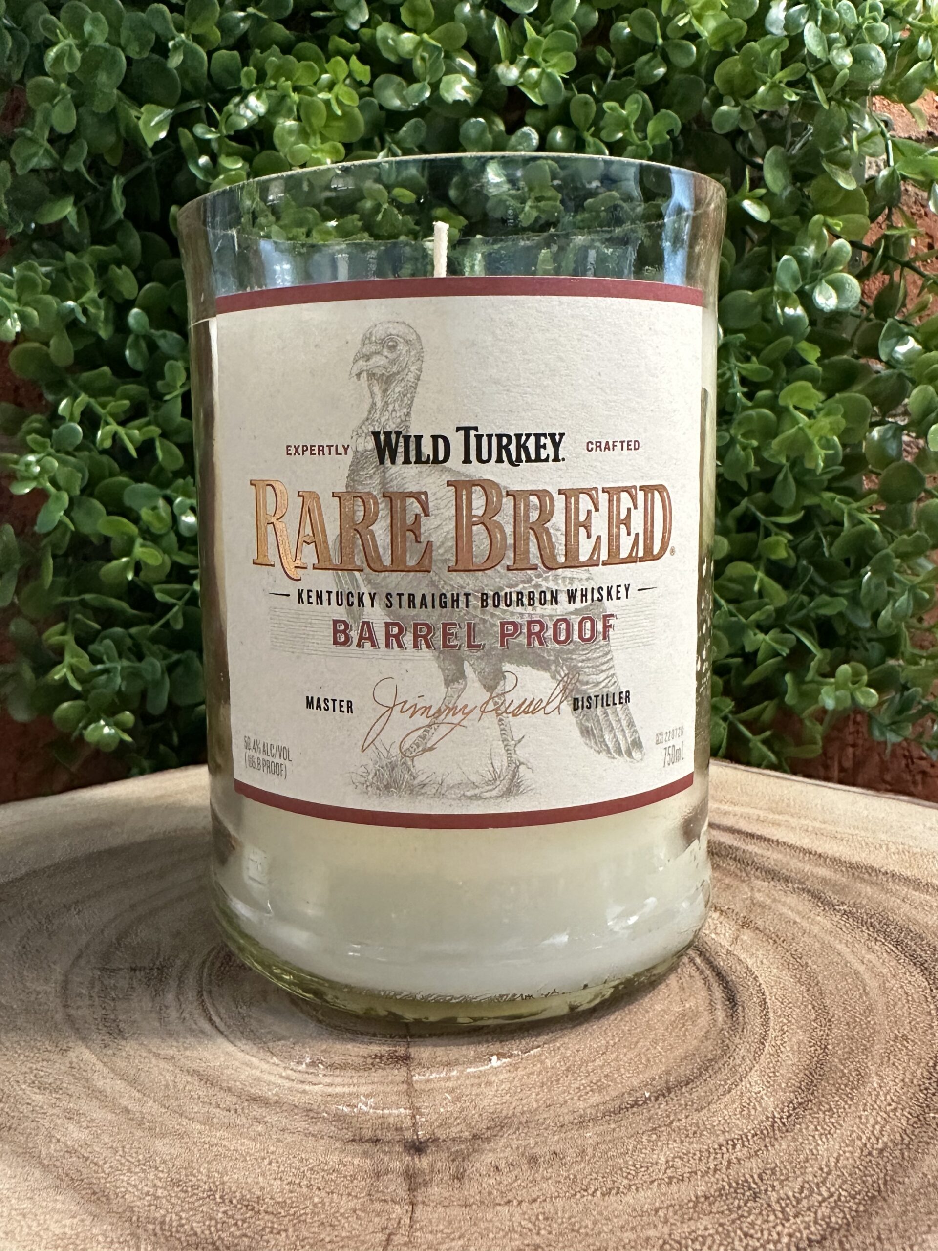 Custom bottle candles created from an upcycled Wild Turkey Rare Breed Barrel Proof bourbon bottle with off-white wax, highlighting professional glass bottle cutting service craftsmanship.