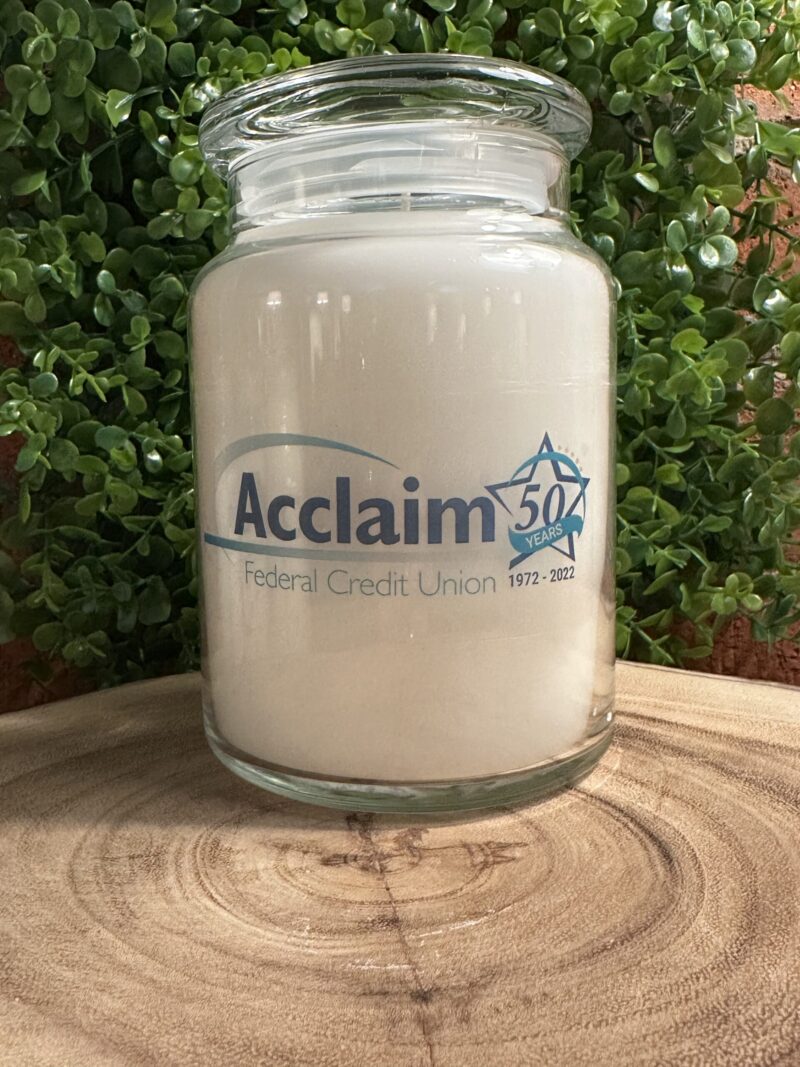 One of The Lighthouse Candle Factory's Custom Corporate Candle Gifts inside a clear glass jar with white wax featuring the Acclaim Federal Credit Union 50th Anniversary logo.