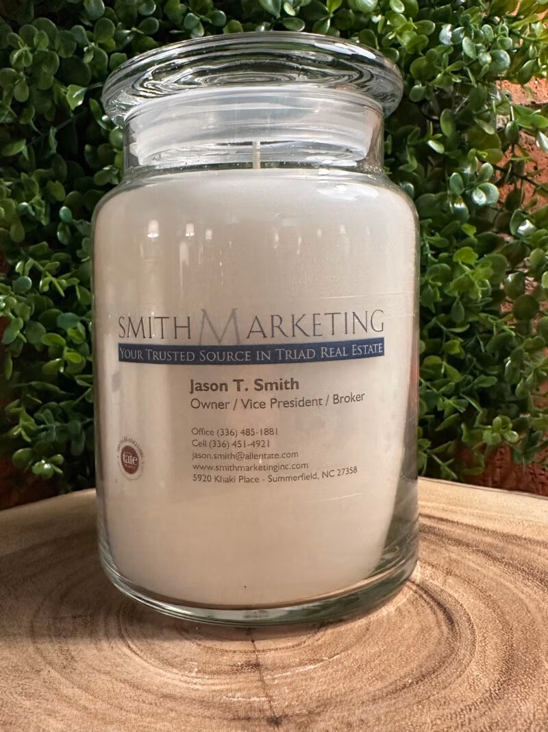 One of The Lighthouse Candle Factory's Custom Corporate Candle Gifts inside a clear glass jar with white wax featuring the Jason Smith logo.