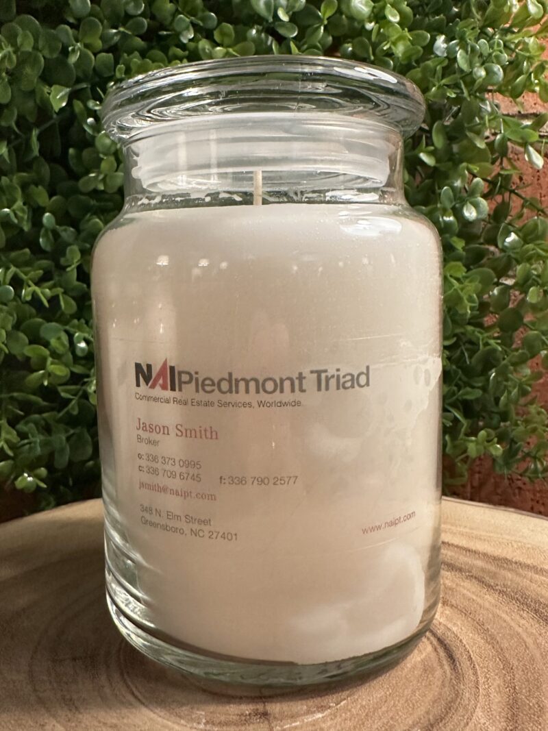One of The Lighthouse Candle Factory's Custom Corporate Candle Gifts inside a clear glass jar with white wax featuring the Jason Smith logo.