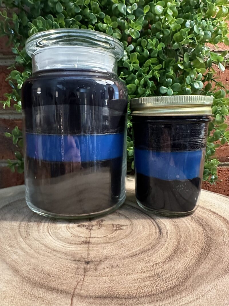 The Thin Blue Line custom candles in a glass apothecary jar and a mason jar, showcasing hand-poured custom candles from The Thin Line Collection for first responders and charity programs.