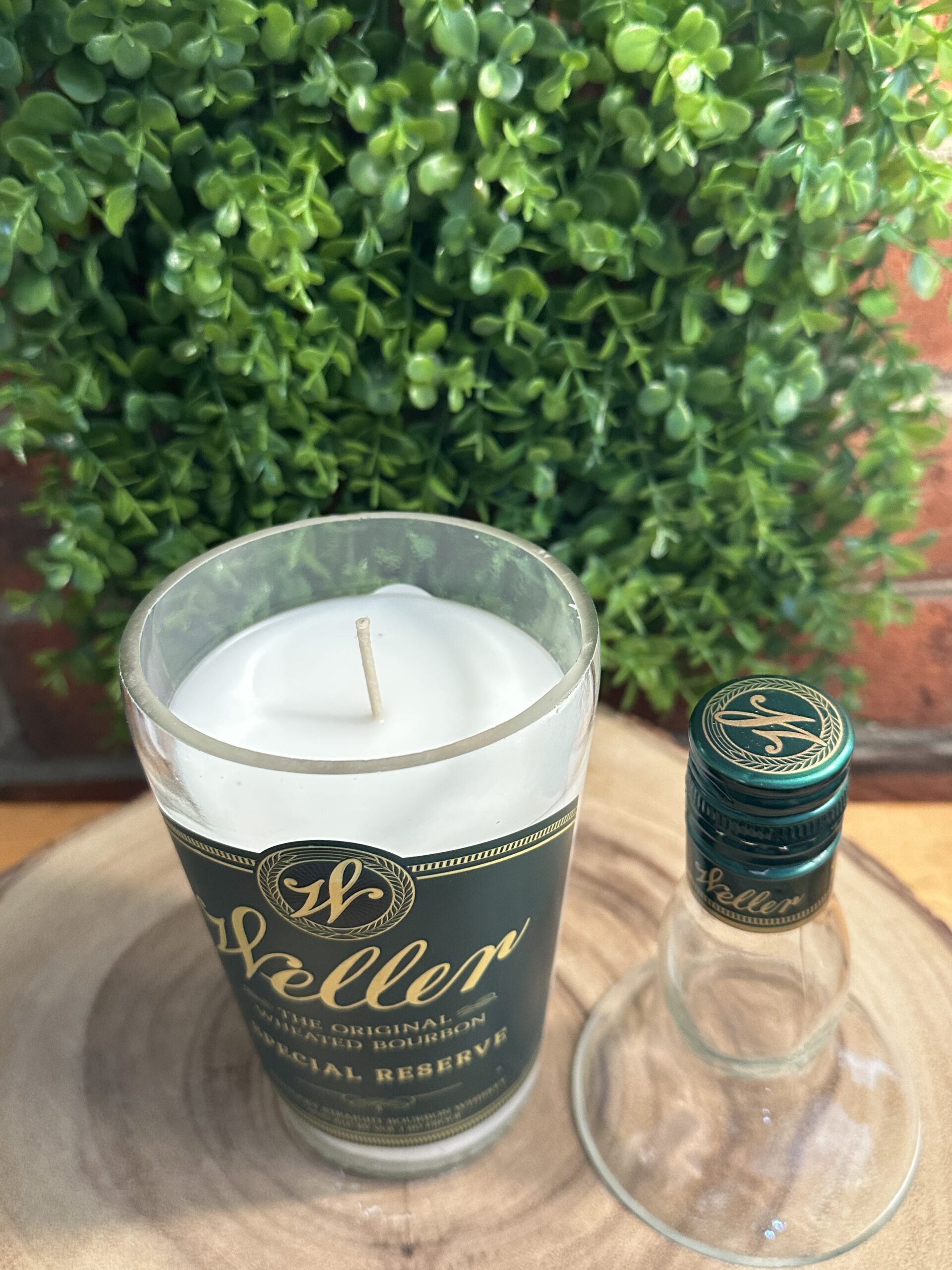 Custom bottle candles created from an upcycled W.L. Weller Special Reserve bourbon bottle featuring crisp white wax alongside the cut-off bottleneck, highlighting precision liquor bottle upcycling.