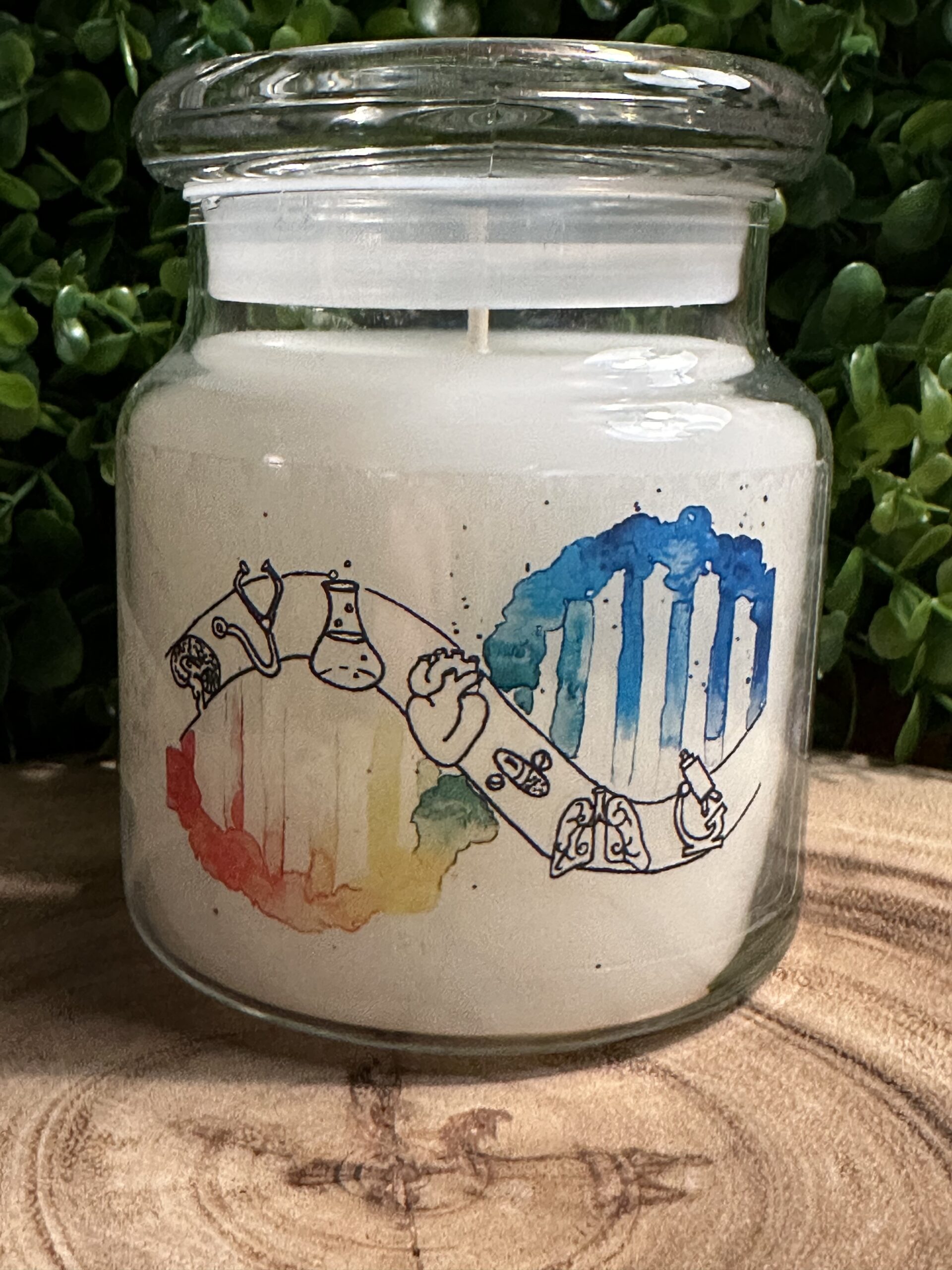 One of The Lighthouse Candle Factory's Custom Corporate Candle Gifts inside a clear glass jar with white wax featuring the logo of the Emergency Medicine Clinical Research Team at a leading North Carolina Trauma Center.