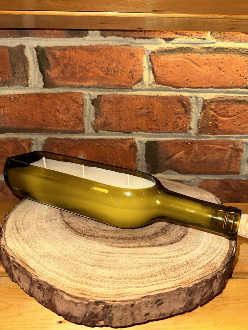 One of The Lighthouse Candle Factory's Custom Corporate Candle Gifts inside a green wine bottle that was custom cut in-house to create a 3-Wick Wine Boat Candle. Filled with white wax featuring and Lemongrass fragrance.