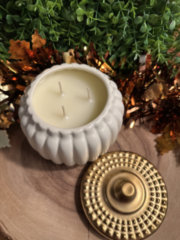 Grandpa's Apple Cider Candle in a ivory pumpkin-shaped jar with three unlit wicks and a gold lid beside it