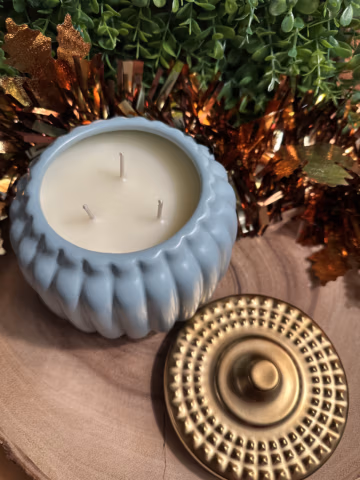 Grandpa's apple cider scented candle in a teal pumpkin-shaped vessel with three unlit wicks and a gold lid beside it