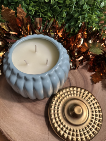 pumpkin pie scented candle in a ribbed teal pumpkin-shaped jar with three unlit wicks and a gold-colored lid beside it