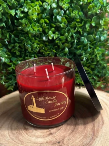 Apple Cinnamon Candle viewed from above with three unlit wicks, crimson red wax and a black lid leaning beside the clear vessel.