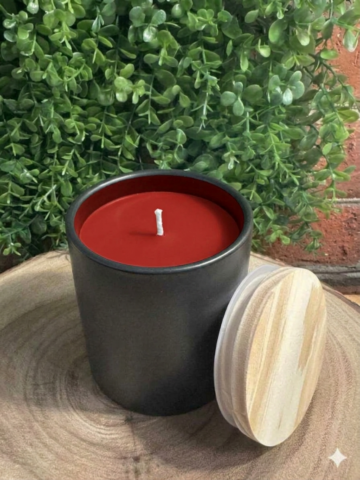 Apple Cinnamon Candle in a black tumbler with visible crimson red wax and a lid beside it