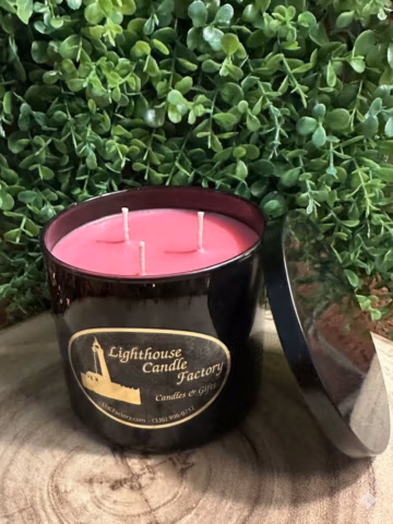 Amaretto Delight almond vanilla candle in a black vessel with pink wax, three unlit wicks and lid leaning beside it