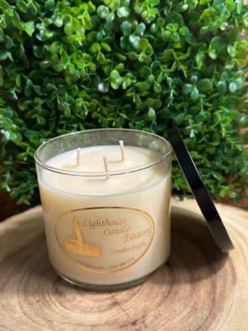 Amazing Grace Floral Musk Candle viewed from above with three unlit wicks and a black lid leaning beside the clear vessel.