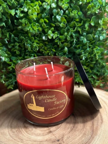 Apple Bourbon Candle viewed from above at an angle, showing three unlit wicks and Chili Red wax, with a black lid leaning beside it.