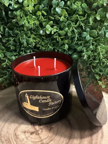 Apple Cinnamon Candle in a black vessel with exposed red wax and three unlit wicks, lid leaning beside it.