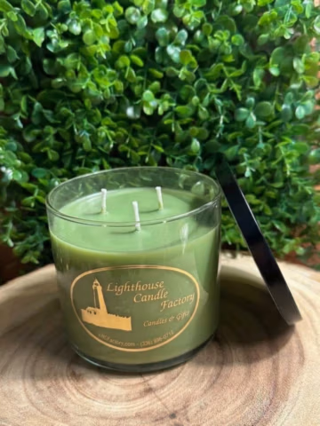 Bayberry scented candle with three unlit wicks in a clear vessel, black lid leaning beside it.
