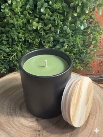 Bayberry Scented Candle in a black ceramic tumbler, unlit with green wax and a wooden lid leaning beside it.