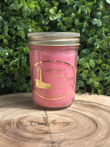 Berry Margarita Candle with Flamingo Pink wax and a gold lid, viewed from the front on a wood slice.