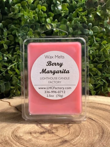 Berry Margarita Wax Melts in a closed clear clamshell on a wood slice against green foliage.